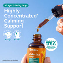 Brown glass bottle of calming drops with dropper dispensing liquid, held in hand against blue background.